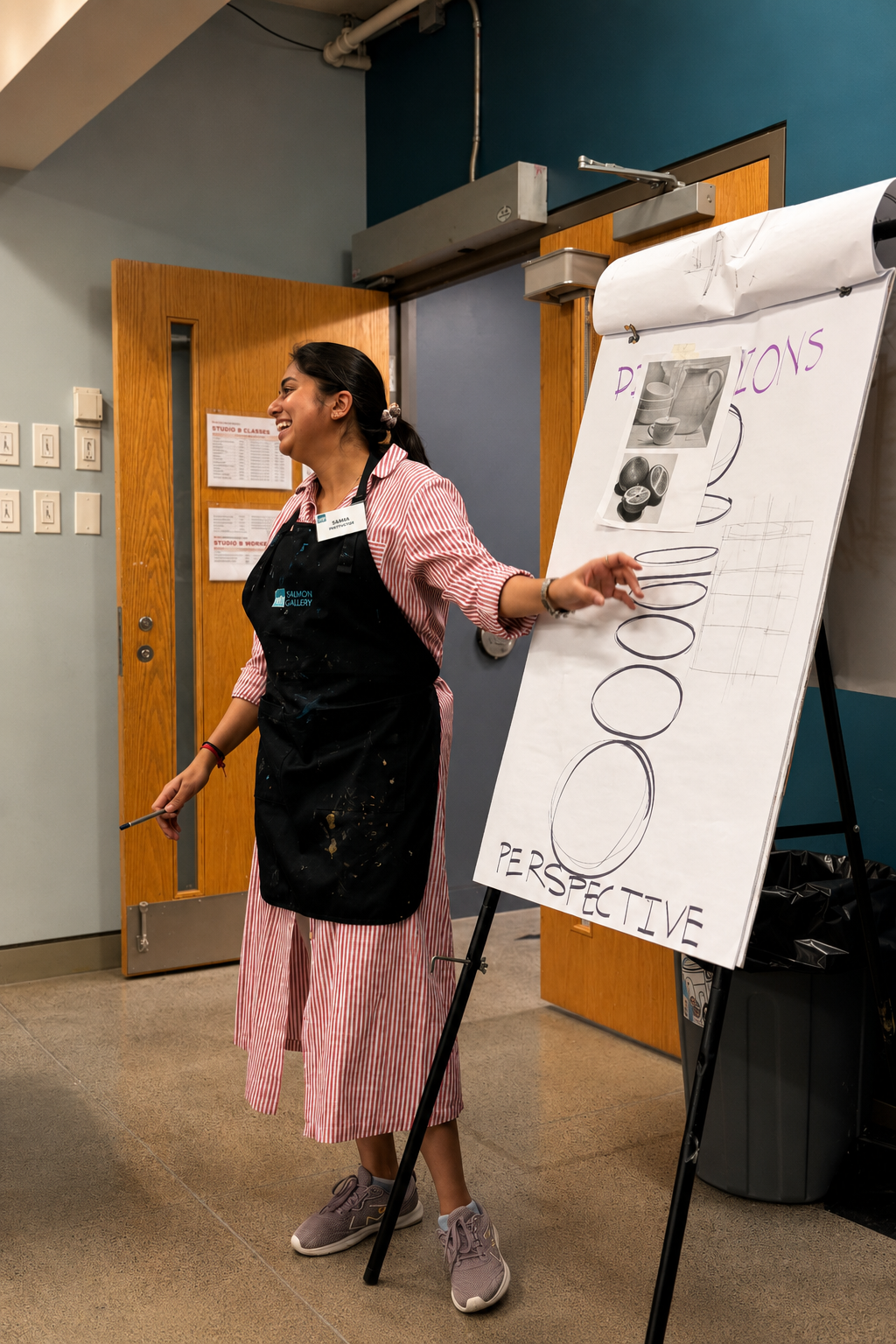 Sakshi Jain demonstrating perspective and dimensions beside a classroom easel.