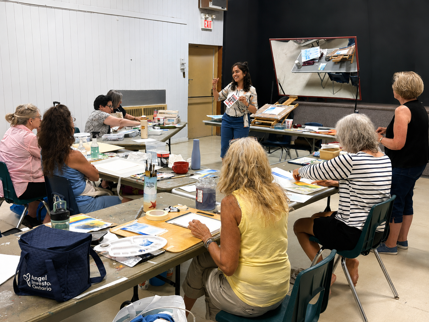 Sakshi Jain leading an adult art workshop around shared studio tables.
